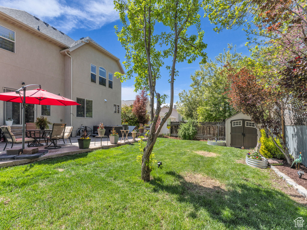 View of yard with a fenced backyard, a storage unit, an outdoor structure, and a patio area