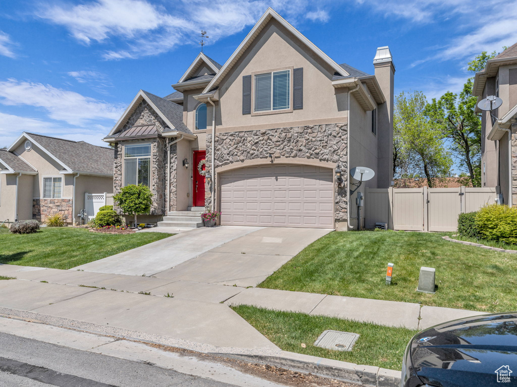 View of front of house featuring fence, a front lawn, stone siding, stucco siding, and a gate