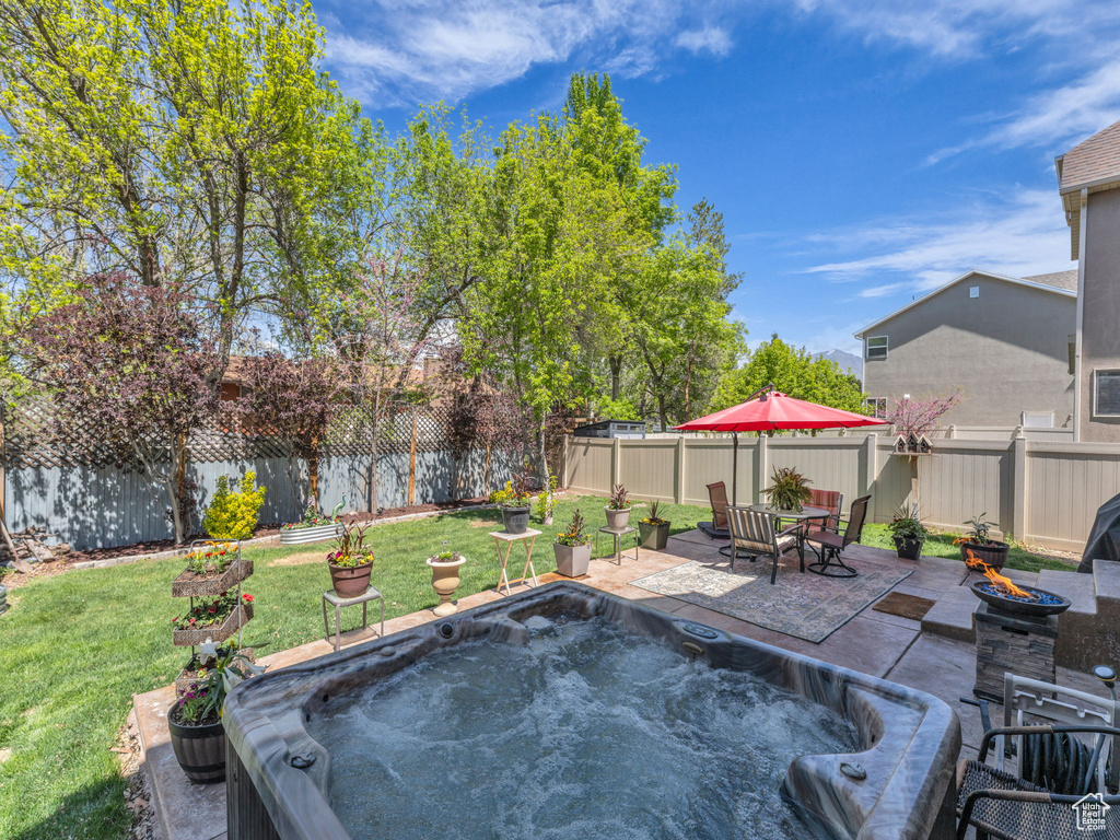 Exterior space featuring a fenced backyard, a hot tub, and a fire pit