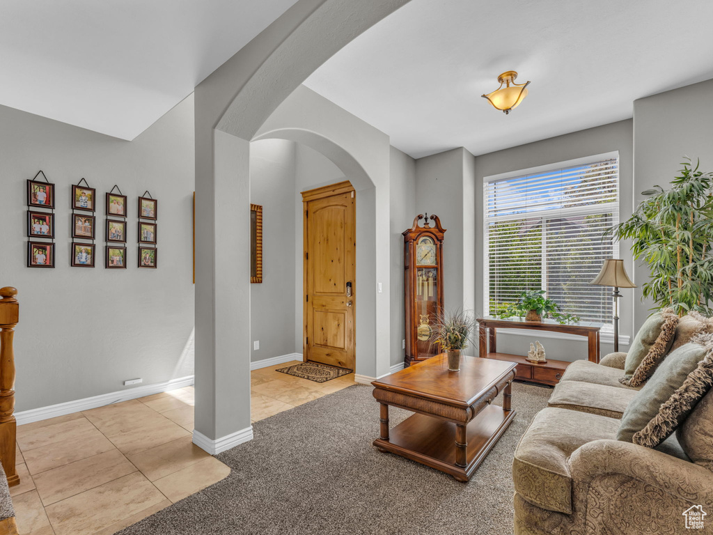 Living room featuring baseboards, arched walkways, carpet, and tile patterned floors