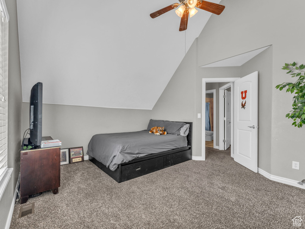 Carpeted bedroom with baseboards, visible vents, ceiling fan, and lofted ceiling