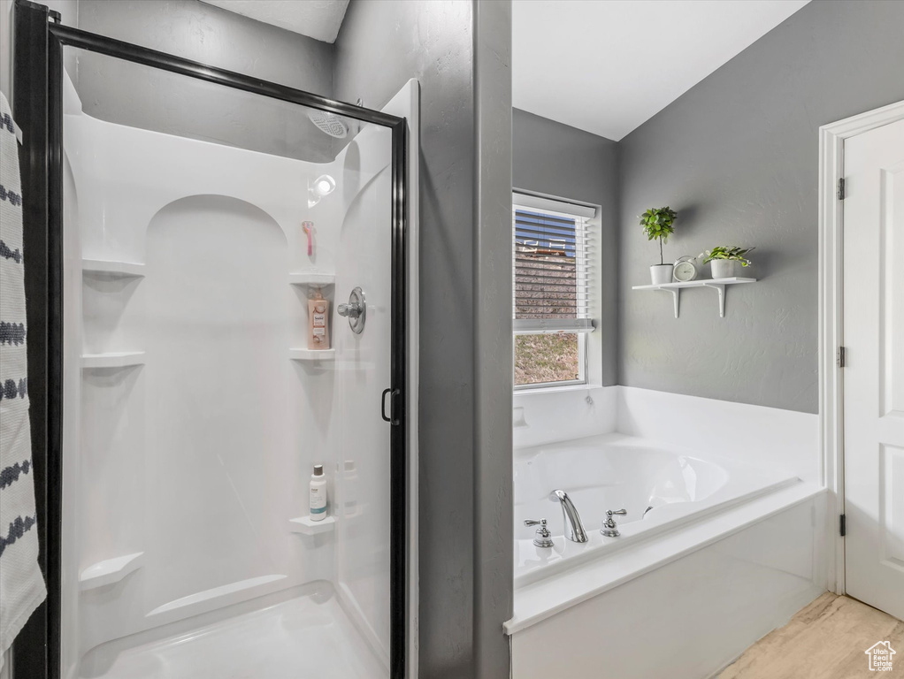 Full bathroom featuring a shower stall, wood finished floors, and a bath