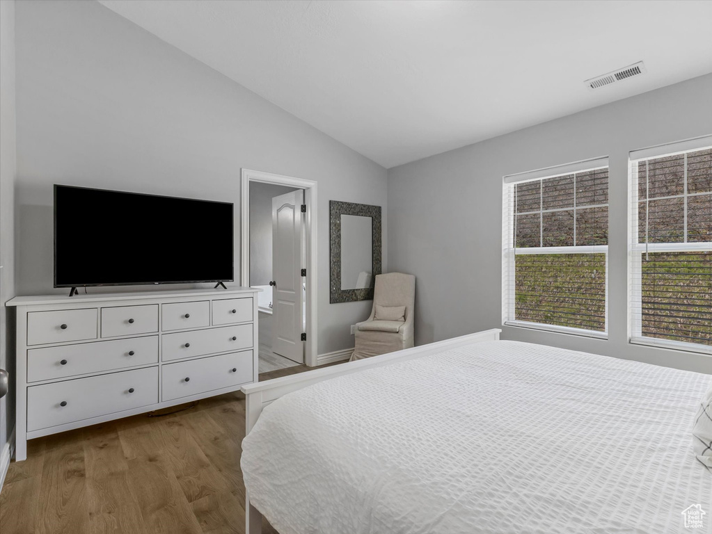 Bedroom featuring vaulted ceiling, wood finished floors, and visible vents