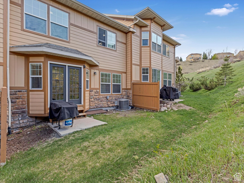 Rear view of property featuring a yard, a patio, board and batten siding, and stone siding