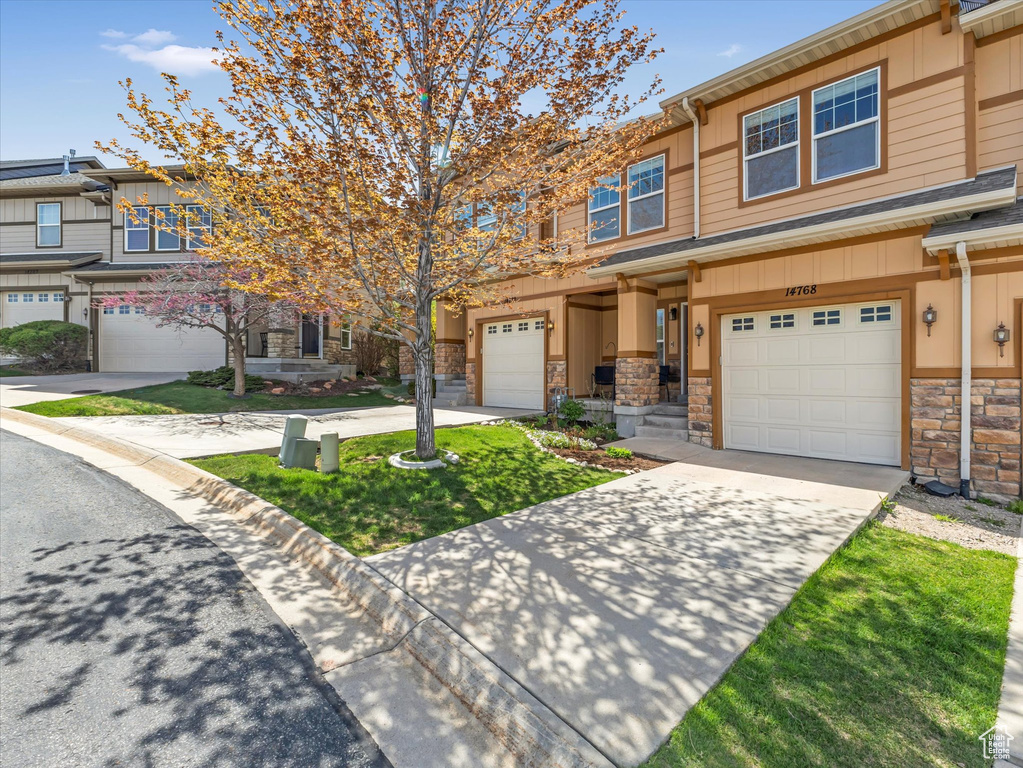 Multi unit property featuring concrete driveway, stone siding, and a garage