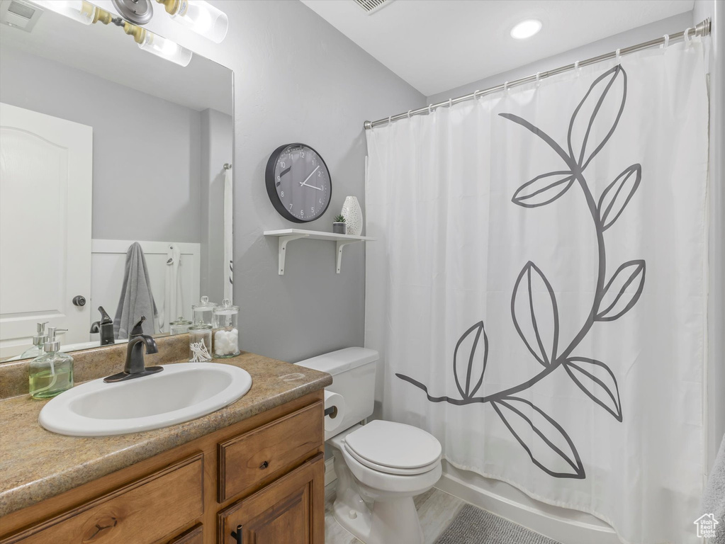 Full bathroom featuring toilet, visible vents, shower / tub combo, and vanity