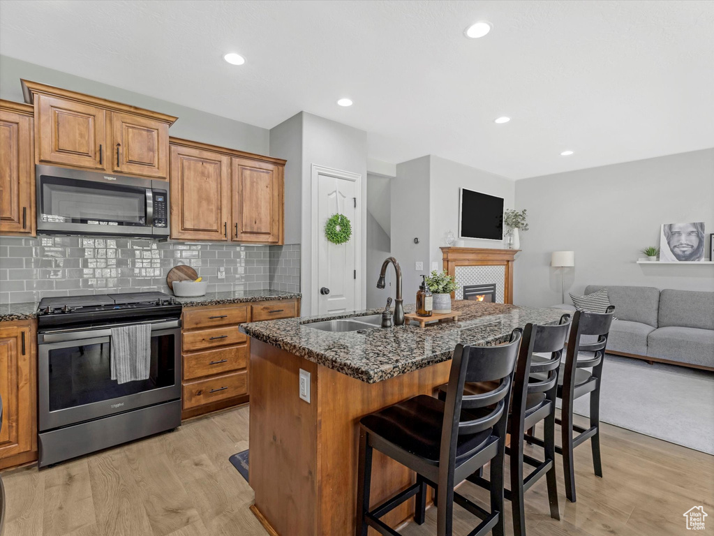 Kitchen featuring a sink, dark stone counters, open floor plan, and stainless steel appliances