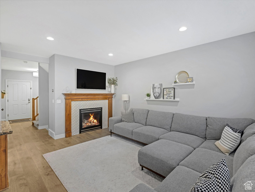 Living room with recessed lighting, baseboards, light wood finished floors, and a fireplace