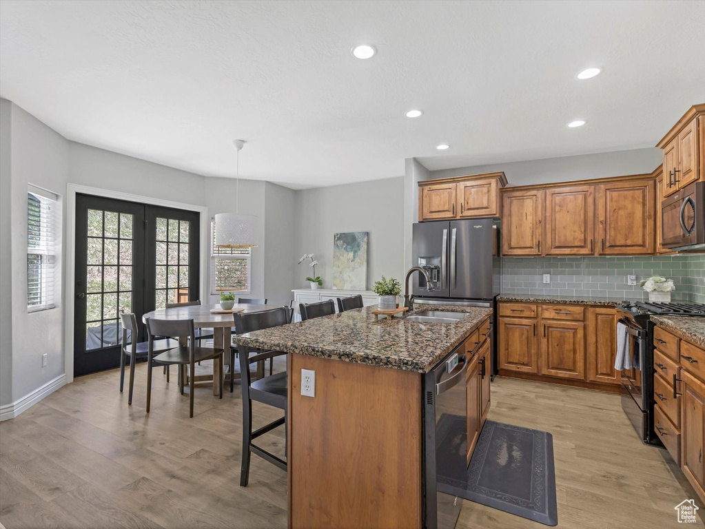Kitchen featuring a sink, appliances with stainless steel finishes, light wood-type flooring, and brown cabinets