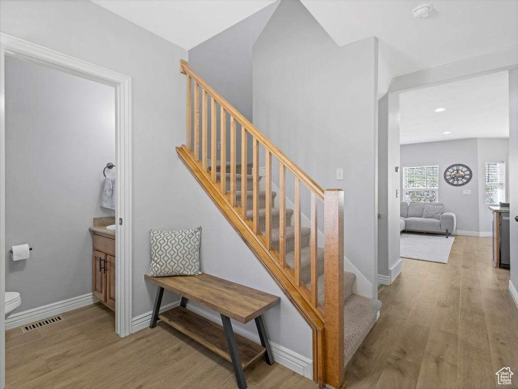 Stairway with baseboards, wood finished floors, and visible vents