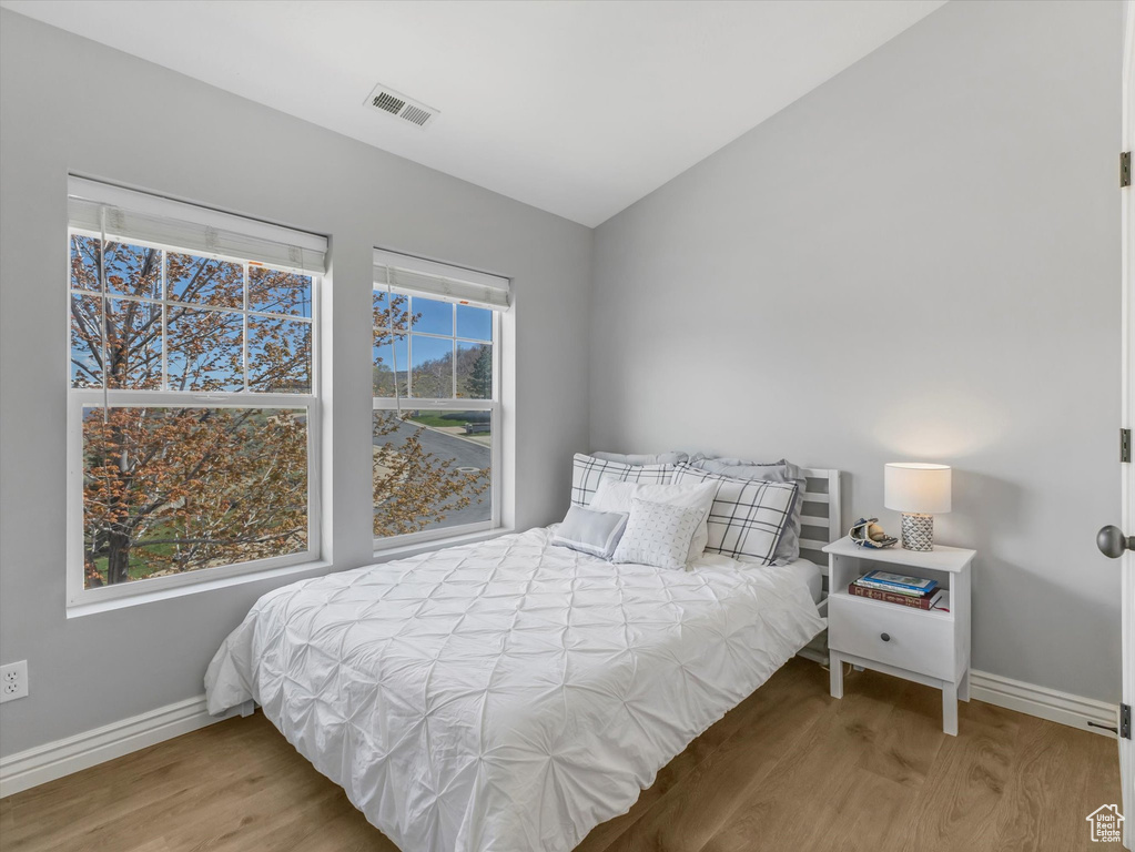 Bedroom featuring visible vents, baseboards, lofted ceiling, and wood finished floors