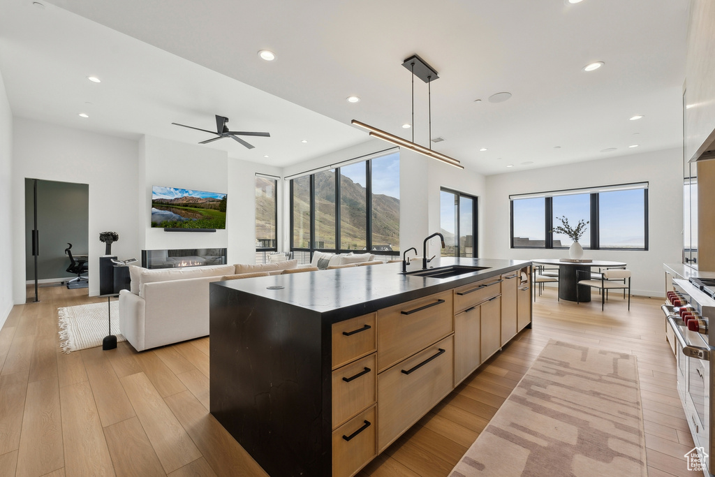 Kitchen featuring light brown cabinetry, dark countertops, a sink, double oven range, and modern cabinets