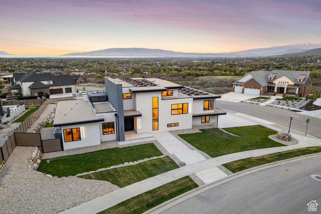 View of front of home with fence private yard, stucco siding, a mountain view, a yard, and a residential view