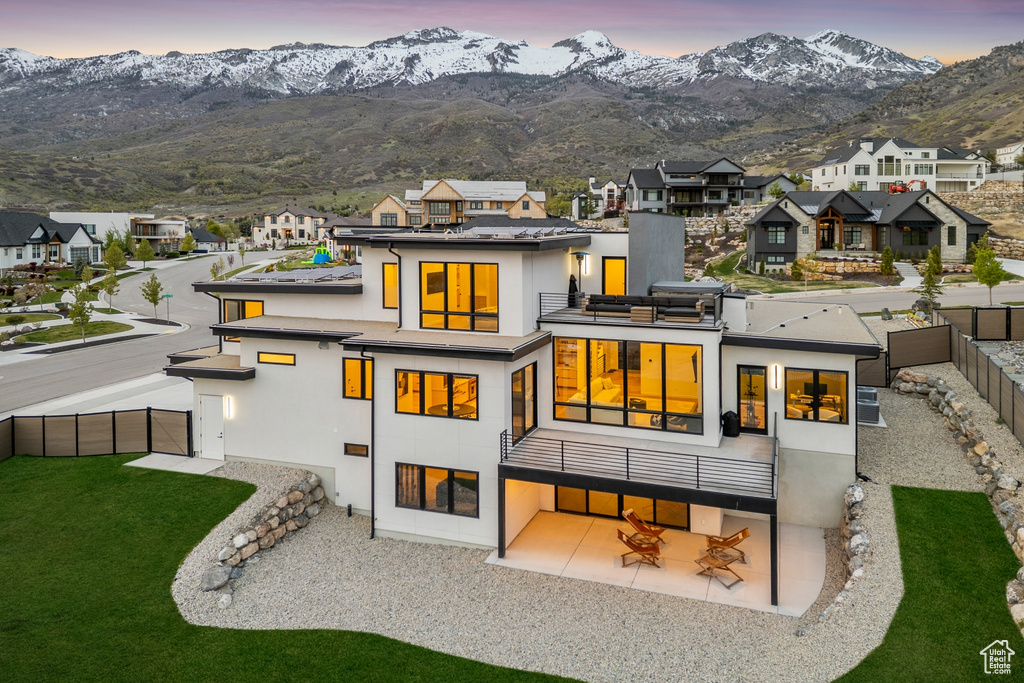Rear view of property with a patio area, a fenced backyard, a mountain view, a balcony, and stucco siding