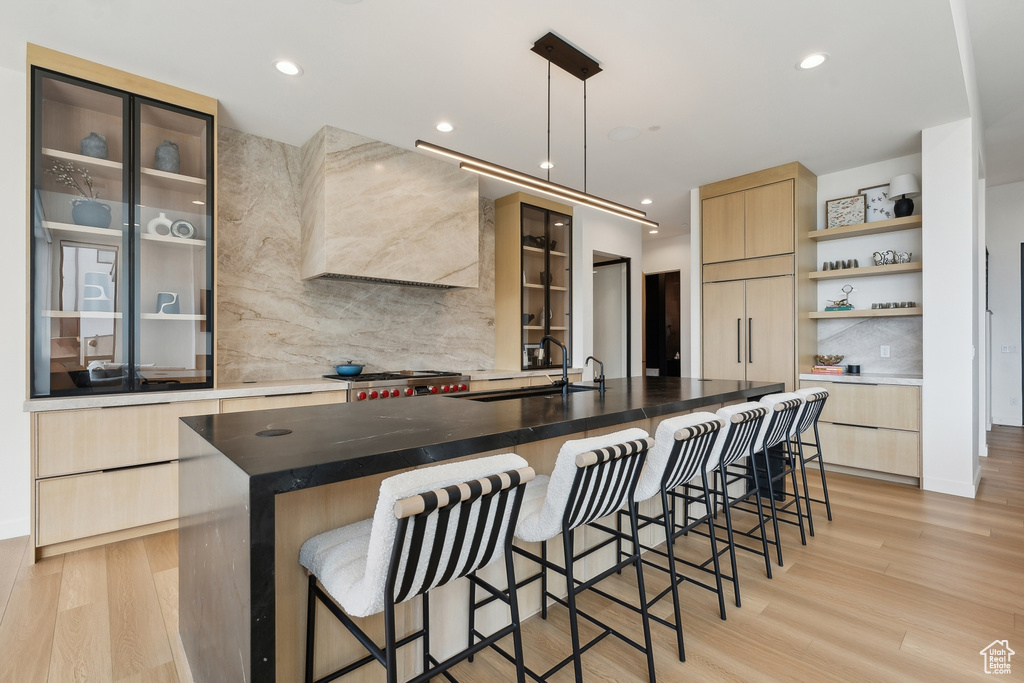 Kitchen featuring a sink, modern cabinets, light brown cabinetry, and tasteful backsplash