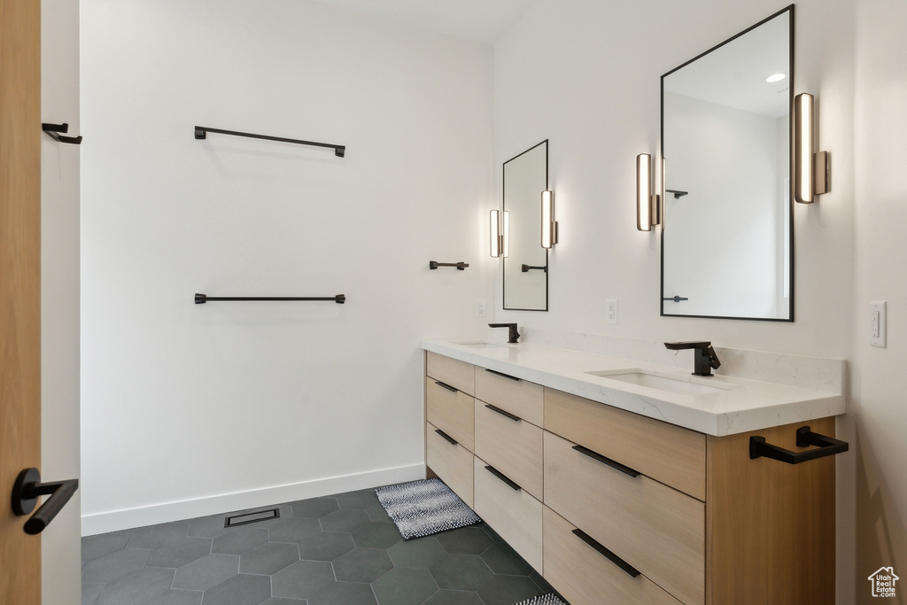 Full bathroom with double vanity, baseboards, a sink, and tile patterned floors