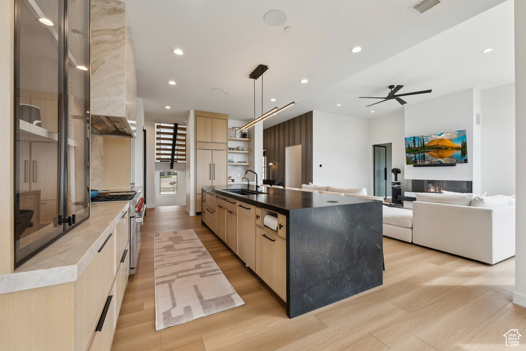 Kitchen featuring light brown cabinetry, modern cabinets, and high end stove