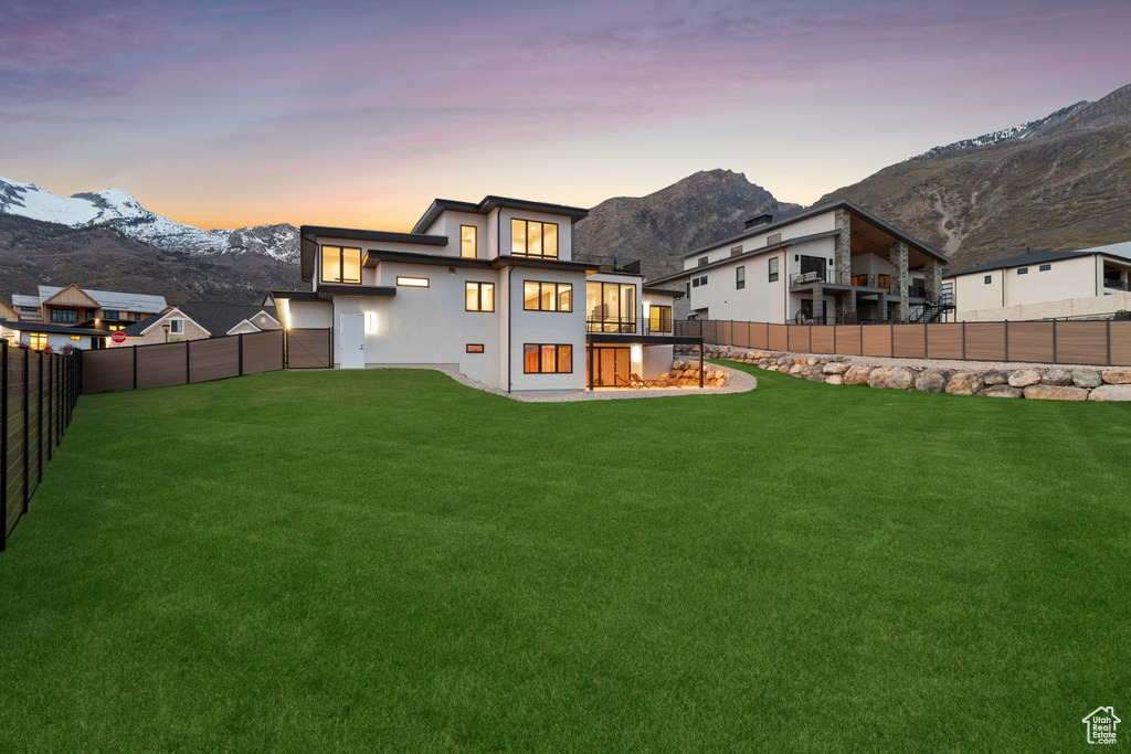 Back of property with stucco siding, a fenced backyard, a mountain view, and a yard