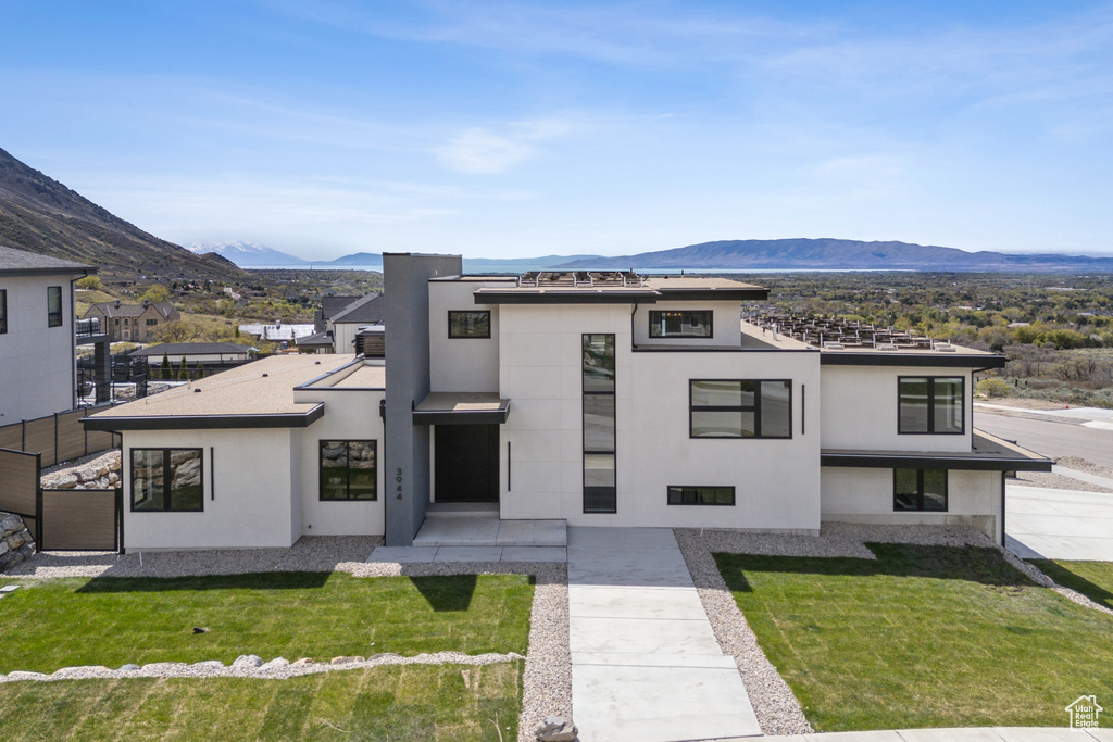 View of front of house featuring a front lawn, a mountain view, and stucco siding