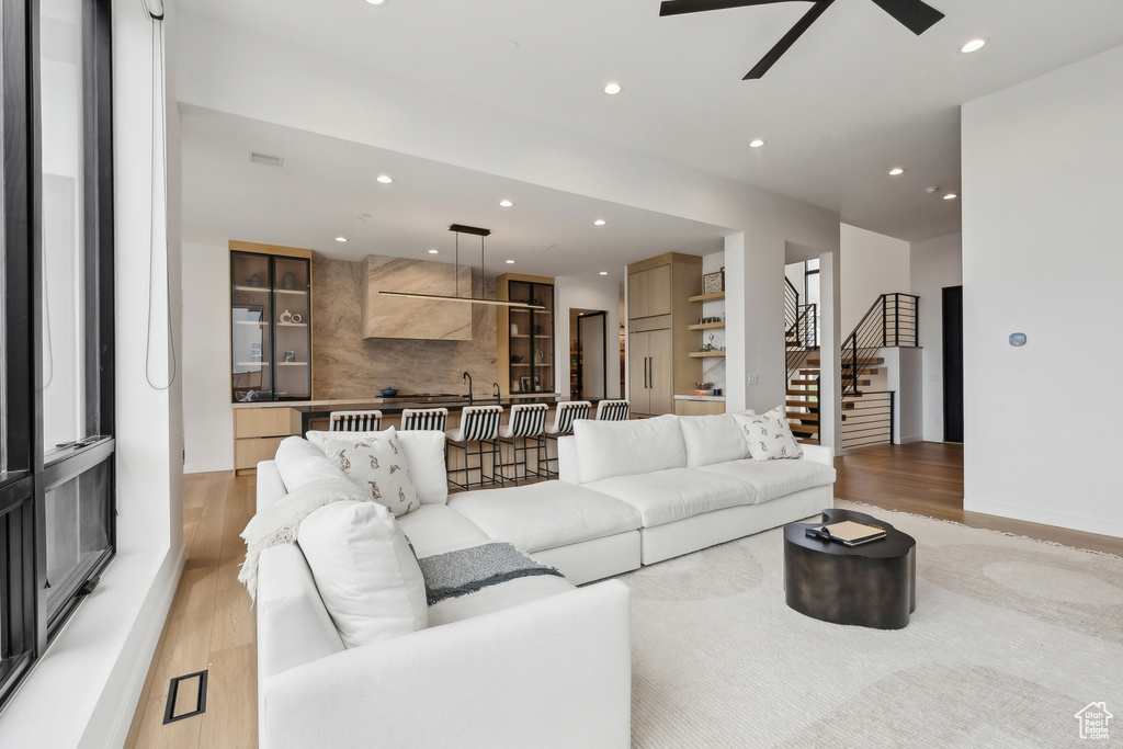 Living room featuring recessed lighting, ceiling fan, light wood-style flooring, and stairway