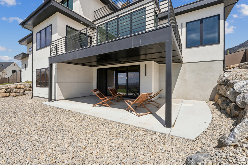 Back of house with a patio, stucco siding, and a balcony