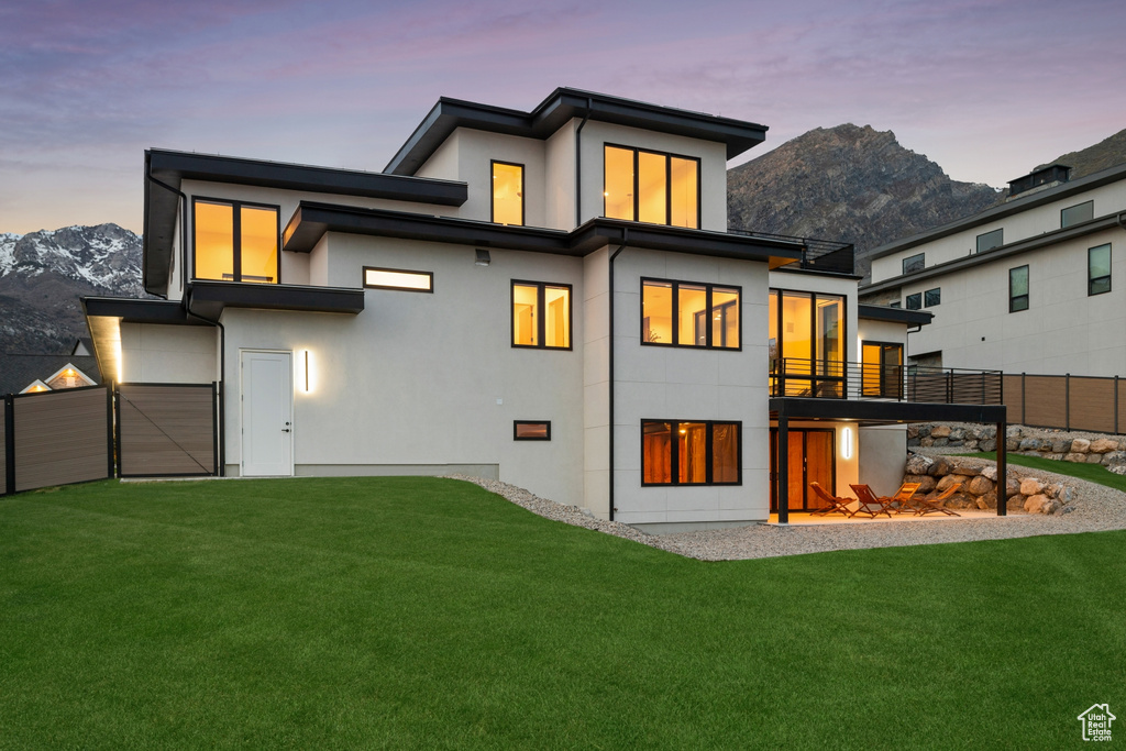 Back of property with a mountain view, stucco siding, and a yard