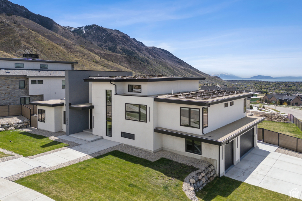 Modern home featuring stucco siding, a mountain view, driveway, and fence