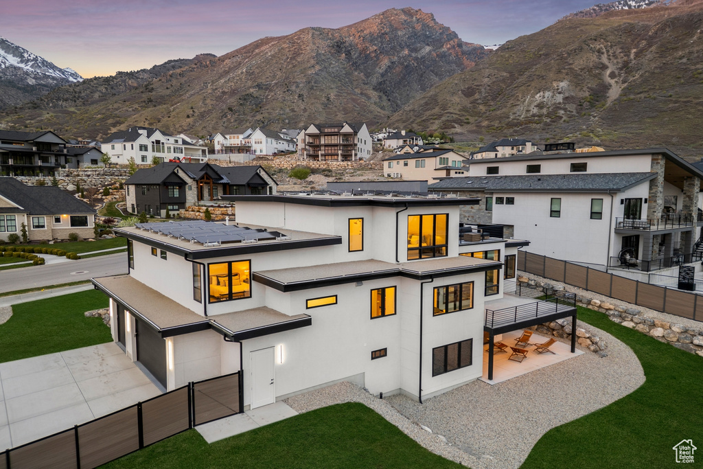 Rear view of property featuring a residential view, a garage, a mountain view, a fenced backyard, and stucco siding