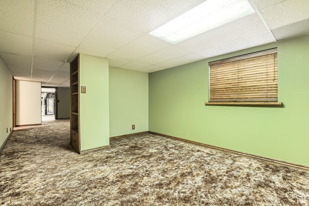 Basement with carpet floors, baseboards, and a drop ceiling