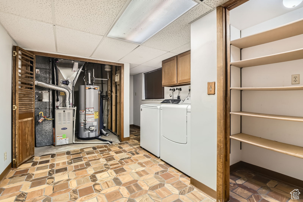 Laundry room with heating unit, cabinet space, water heater, and washer and dryer