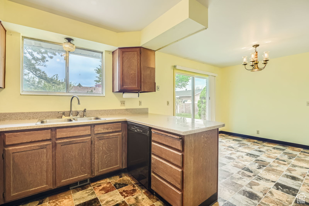 Kitchen featuring a peninsula, light countertops, a sink, dishwasher, and a notable chandelier
