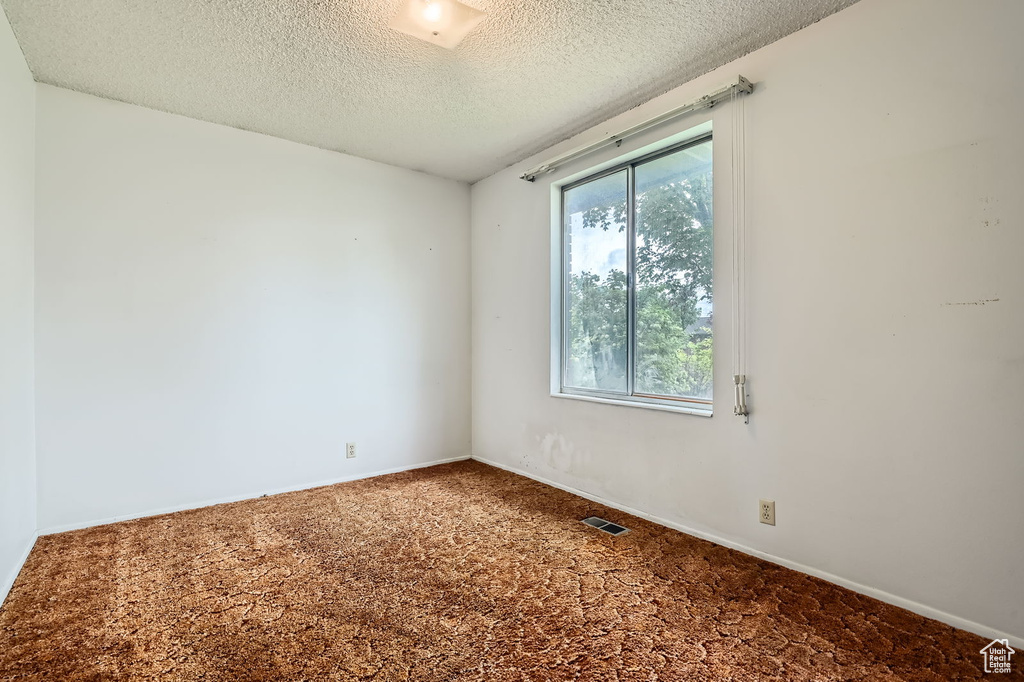 Spare room with baseboards, a textured ceiling, and visible vents