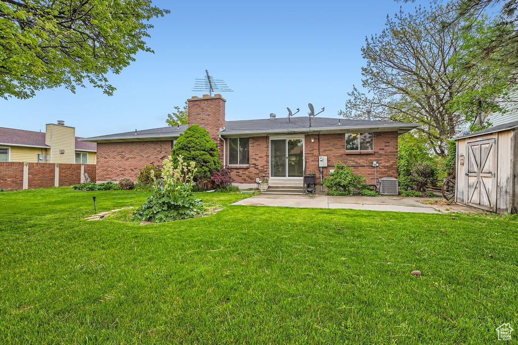 Rear view of property featuring a chimney, a shed, a yard, a patio, and entry steps