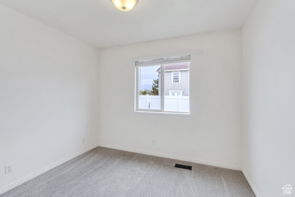 Carpeted empty room featuring visible vents and baseboards