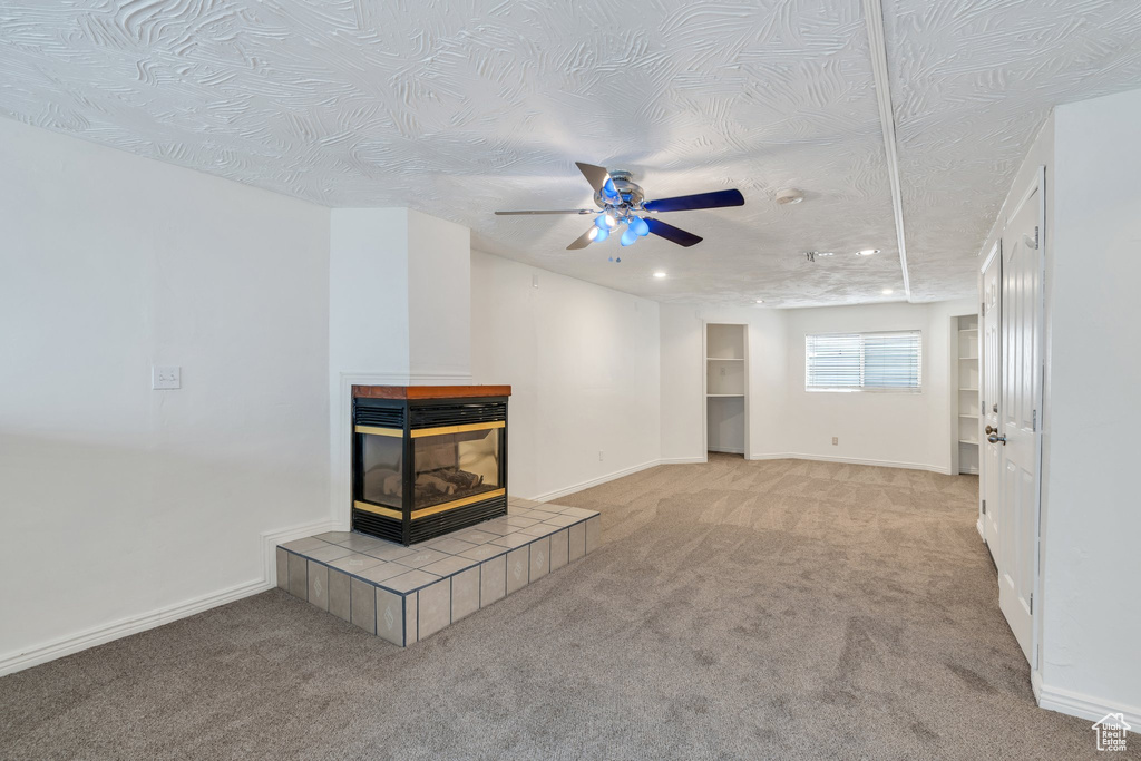 Unfurnished living room featuring baseboards, a textured ceiling, carpet, and ceiling fan