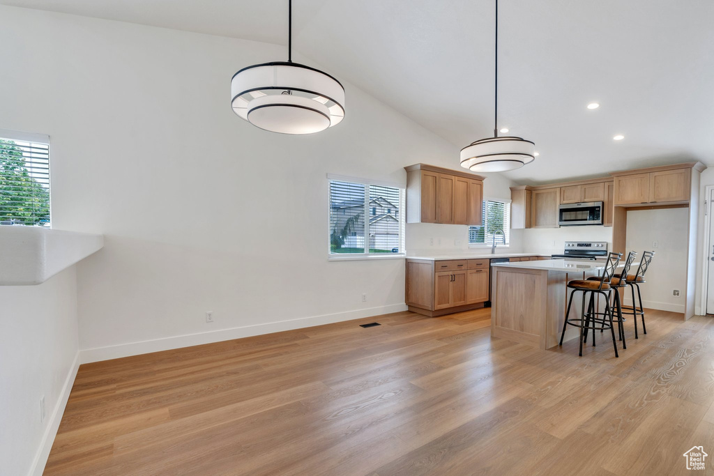 Kitchen with light countertops, appliances with stainless steel finishes, baseboards, and light wood-style flooring