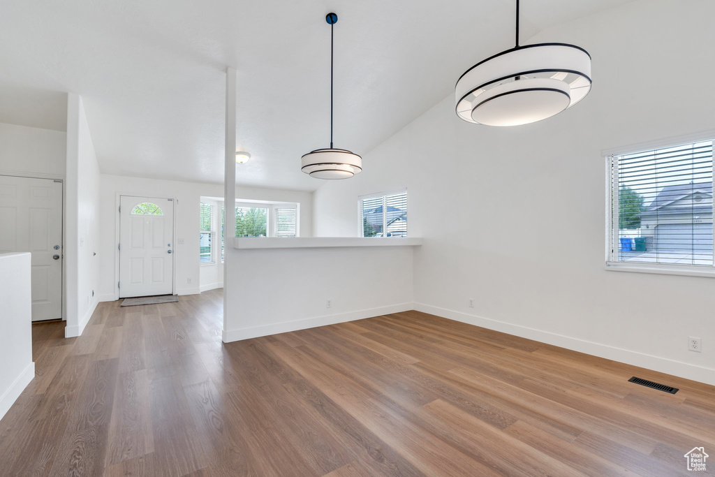 Interior space with baseboards, lofted ceiling, wood finished floors, and visible vents