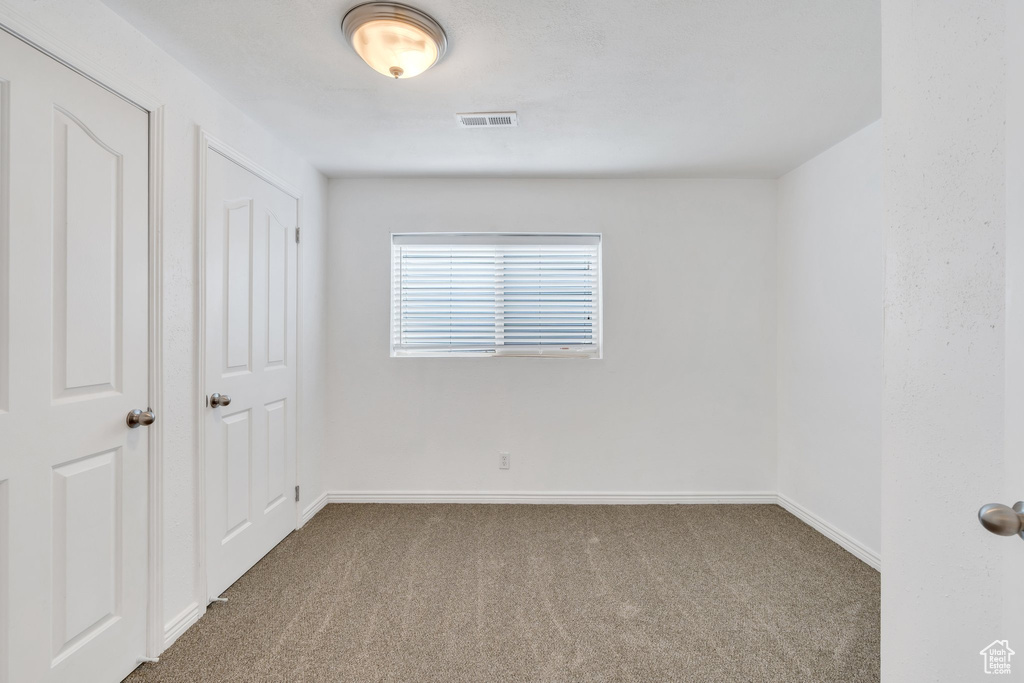 Empty room featuring visible vents, carpet, and baseboards