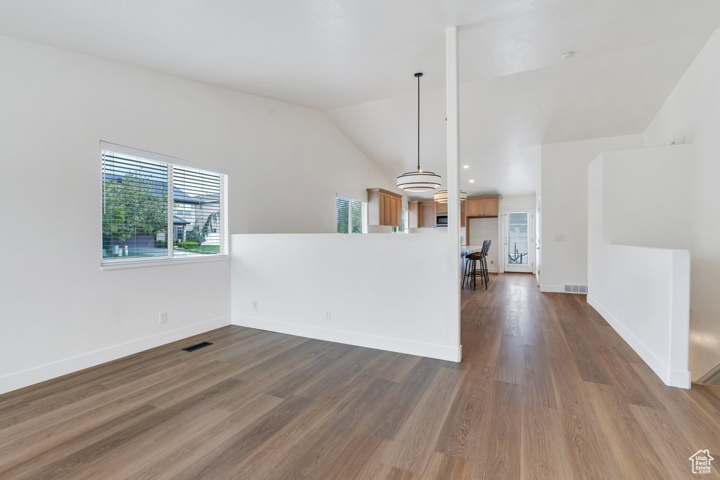 Empty room featuring baseboards, vaulted ceiling, dark wood-style floors, and visible vents