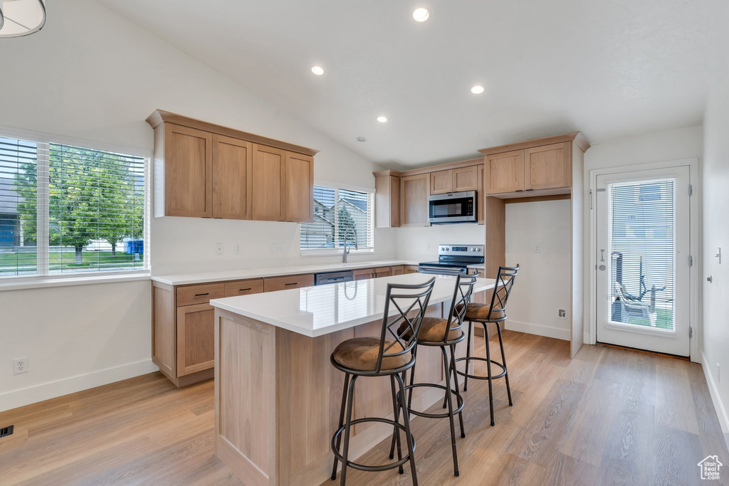 Kitchen with light wood-style floors, baseboards, and appliances with stainless steel finishes