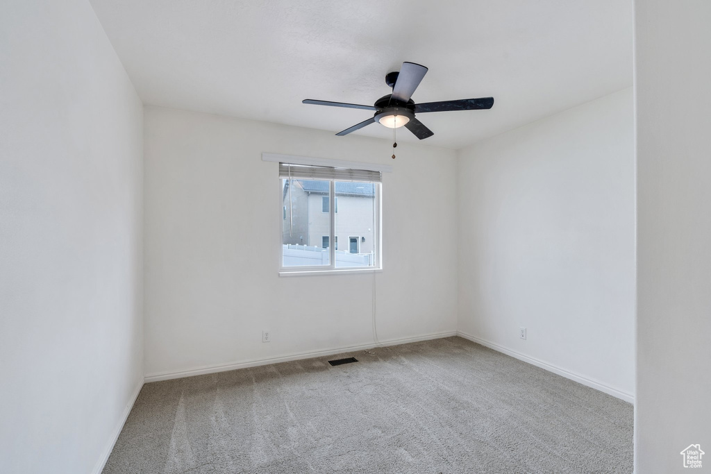 Empty room with visible vents, carpet flooring, baseboards, and a ceiling fan