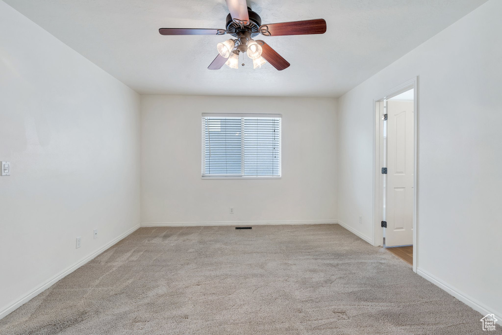 Empty room featuring baseboards, ceiling fan, and carpet