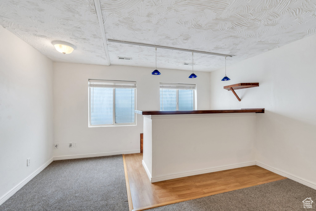 Kitchen featuring baseboards, carpet flooring, a textured ceiling, and pendant lighting