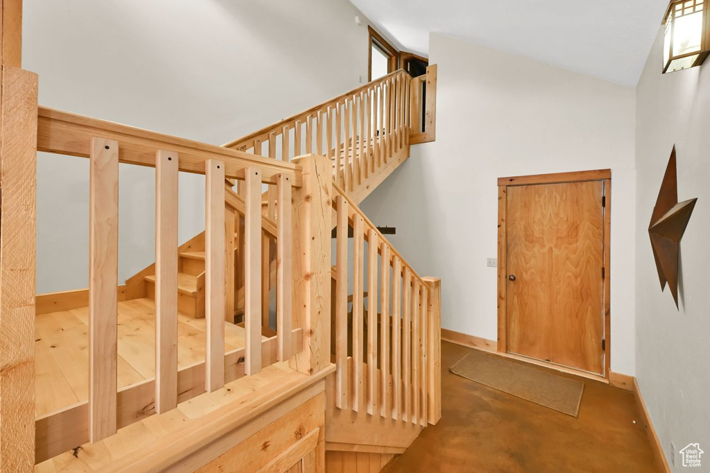 Stairs with baseboards, vaulted ceiling, and finished concrete floors