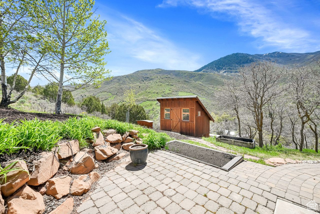 View of patio with a storage shed, an outbuilding, and a mountain view