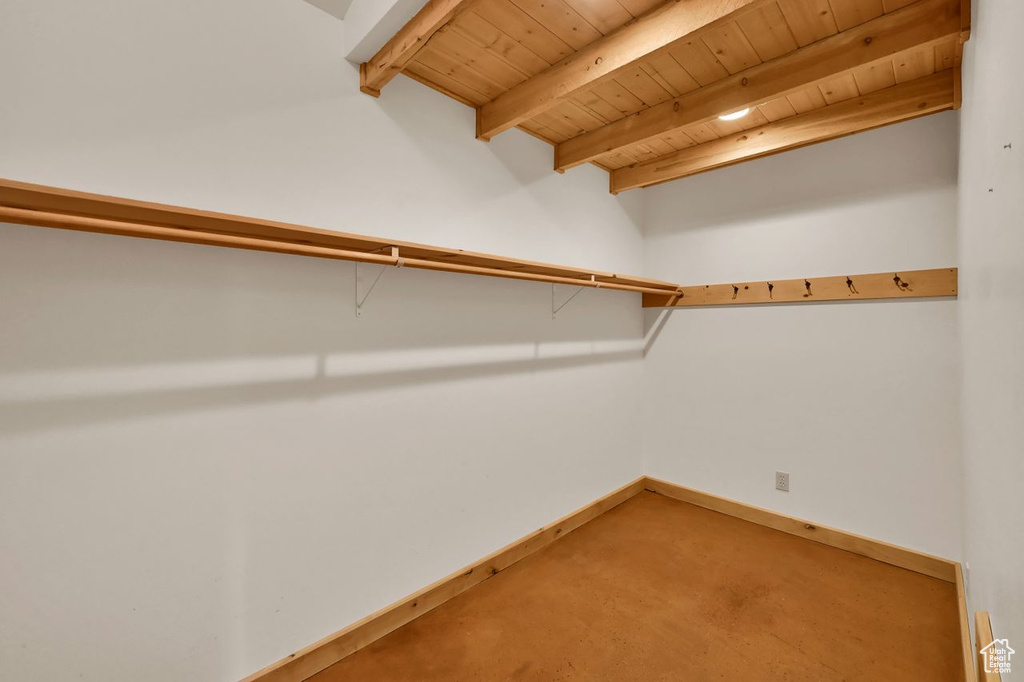 Spacious closet with carpet and beam ceiling