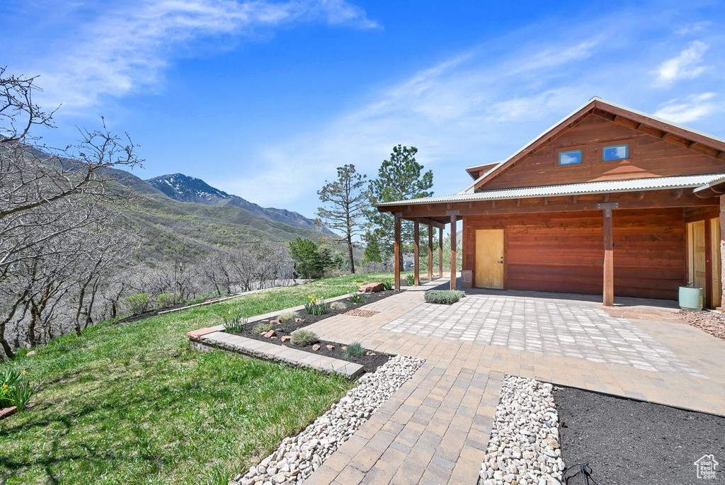 View of side of property with a lawn, a mountain view, and a patio area