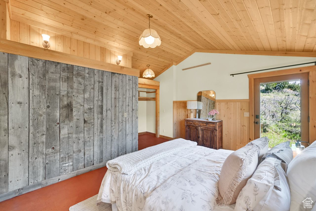 Carpeted bedroom featuring lofted ceiling, wooden walls, access to outside, a wainscoted wall, and wooden ceiling