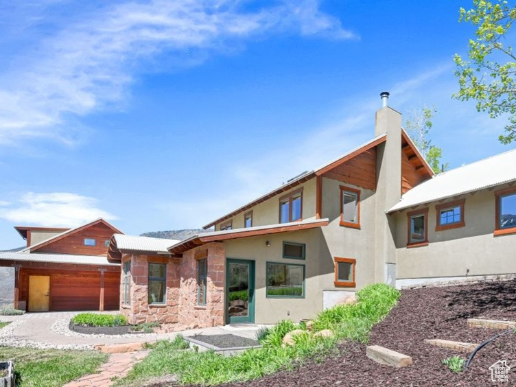 Back of house featuring stucco siding, stone siding, and a garage
