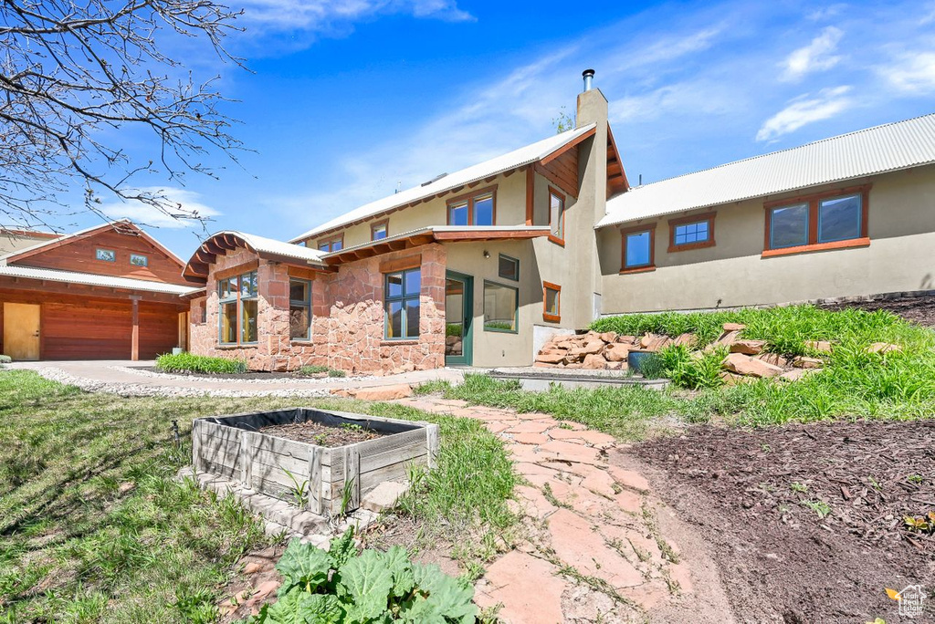 View of front of house featuring a garage, a chimney, and stucco siding